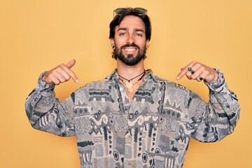 Young handsome hispanic bohemian man wearing hippie style and sunglasses looking confident with smile on face, pointing oneself with fingers proud and happy.