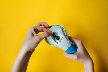 Woman's hands holding a label maker with Hello word typed, on bright yellow background. - obrazy, fototapety, plakaty