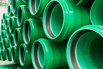 Green plastic pipes lie in rows