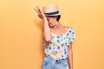 Young beautiful woman wearing summer hat surprised with hand on head for mistake, remember error....