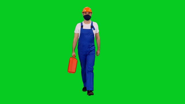 Builder worker in protective mask and hardhat walking with red case on green screen background, Chroma key 