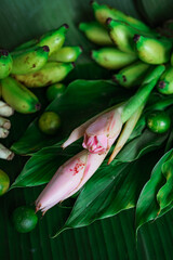 Asian food ingredient with bunga kantan or torch lily, calamansi, lemongrass, tumeric leaves and bananas on a banana leaf background.