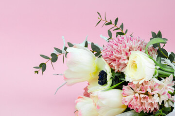 Close-up bouquet of flowers on a pink background, spring tulips of white color with hyacinth and buttercup. Banner with place for text and your advertisement.