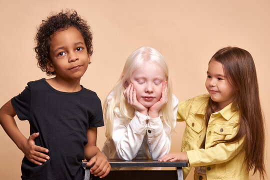 Portrait Of Beautiful Kids With Natural Unusual Appearance. Girl With Albinism Syndrome Is Friends With Black African Boy And American Girl. Children Maintain Tolerance And Kindness To Each Other