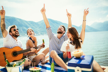 Group of friends with guitar having fun on the beach.