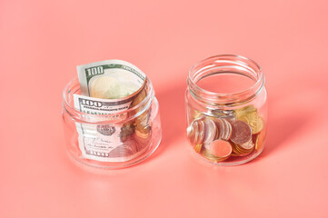 Glass jar with coins and banknote of 100 dollars on pink background. Saving money