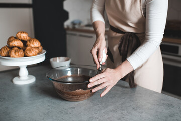 Woman making batter for chocolate cake on kithen table close up. Motherhood. Breakfast time.