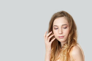 Fototapeta premium A girl with long blond hair on a gray background.