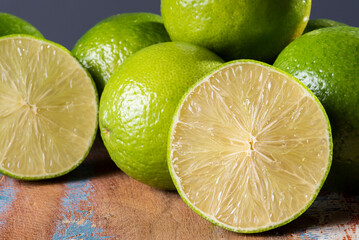 .Lime cut in half with some limes in the background on wooden table.