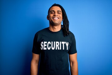 Young african american afro safeguard man with dreadlocks wearing security uniform with a happy face standing and smiling with a confident smile showing teeth