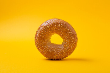 Round bread bagel with sesame seeds on yellow background