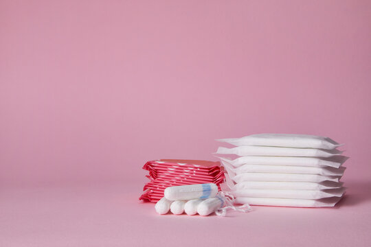 stack of menstrual sanitary cotton pads and tampon on pink background. Feminine hygiene products. copy space.