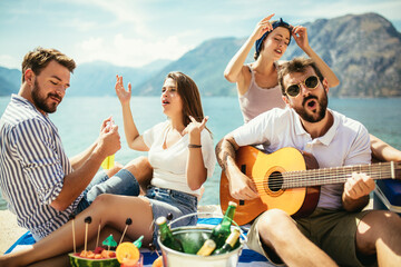 Group of friends with guitar having fun on the beach.