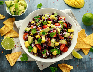 Avocado, mango salad with black bean, tomato, red onion and tortilla chips. healthy food