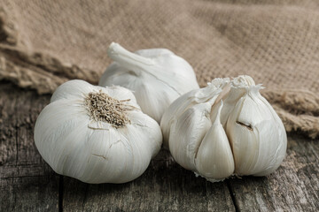 Knoblauch auf rustikalem Hintergrund: dunkles verwittertes Holz und grobe Jute