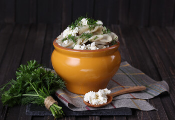 Russian and ukrainian cuisine. Dumplings with cottage cheese and herbs in a pot on an old wooden...