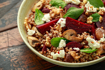 Buckwheat and beetroot salad with mushroom, walnut, spinach and feta cheese on rustic wooden table. healthy diet food