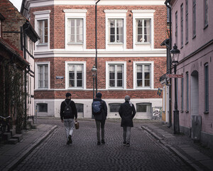 Fototapeta na wymiar Three young male studens walking away from the camera in the old town of university city Lund, Sweden