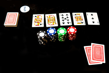 Two cards aces, dealer chip and chips for poker game. Black background, top view.