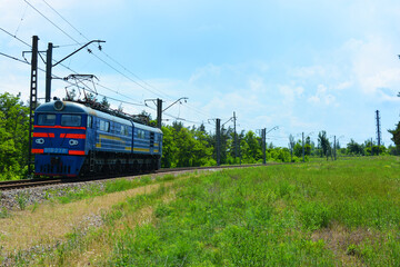 Ukrainian shunting metal blue train travels by rail and is lit by sunlight.