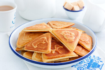 Traditional Russian cookies, cooked on a plate in the form with prints, without baking in an enameled white bowl, selective focus