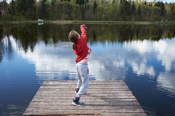 Fototapeta na wymiar Boy throws stones into the lake from the pier.