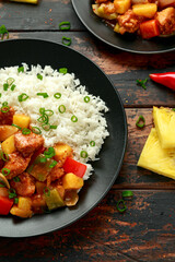 Pineapple and Chicken in sweet and sour sauce with bell pepper, rice and spring onion in black plate