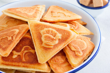 Traditional Russian cookies, cooked on a plate in the form with prints, without baking in an enameled white bowl, selective focus