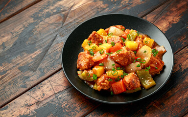 Pineapple and Chicken in sweet and sour sauce with bell pepper in black plate