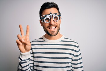 Naklejka premium Young handsome man with beard wearing optometry glasses over isolated white background showing and pointing up with fingers number two while smiling confident and happy.