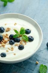 Greek yogurt with granola and blueberries in white bowl. Healthy breakfast food or snack