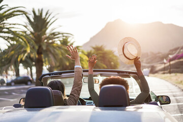 Happy people having fun in convertible car in summer vacation at sunset - Young couple enjoyng ...