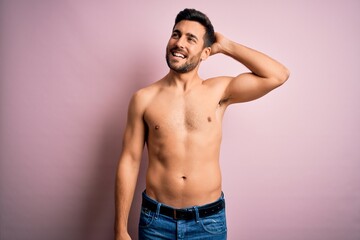 Fototapeta premium Young handsome strong man with beard shirtless standing over isolated pink background smiling confident touching hair with hand up gesture, posing attractive and fashionable