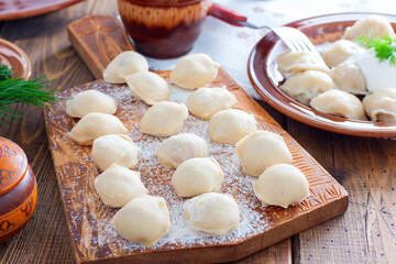 Fototapeta na wymiar Raw homemade dumplings on a wooden board, selective focus