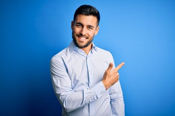 Young handsome man wearing elegant shirt standing over isolated blue background cheerful with a...