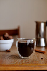 Glass cup with coffee and milk standing in the wooden table with chocolate candies and cinnamone 