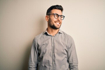 Young handsome man wearing elegant shirt and glasses over isolated white background looking away to...