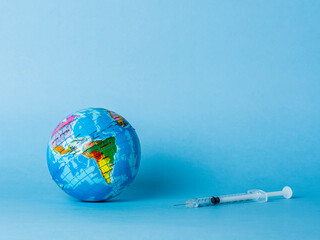 World globe and syringe on a blue background