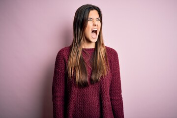 Fototapeta premium Young beautiful girl wearing casual sweater over isolated pink background angry and mad screaming frustrated and furious, shouting with anger. Rage and aggressive concept.