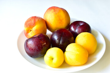Ripe and juicy peaches and apricots on a white plate