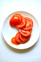 Ripe and juicy tomatoes sliced on a white plate