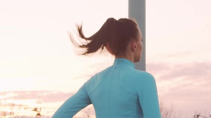 Young, beautiful and sporty woman having evening training outdoor. Urban sunset background.