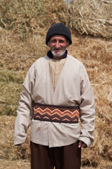 Old farmer man with Hay bales on background. Elderly muslim farmer