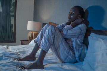 young sad and depressed black African American woman lying on bed at home unhappy and sleepless at...