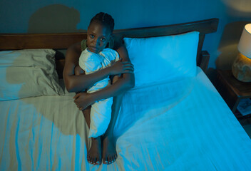 Obraz premium young sad and depressed black African American woman sitting on bed at home sleepless at night feeling overwhelmed suffering depression problem thoughtful
