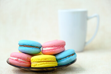 Obraz na płótnie Canvas Colorful french Sweet Pastries Macaroons on glass plate and white coffee cup.