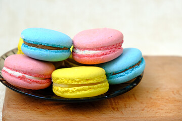 Colorful french Sweet Cakes Macaroons on glass plate on a wooden tray isolated on white background.