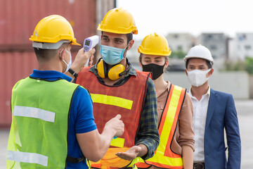 Workers with protective mask, Engineer worker waring surgical mask checking body temperature using infrared digital thermometer check temperature before into work place, - obrazy, fototapety, plakaty