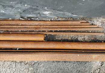 Rusty, old pipes of different diameters lie near the wall, like waste rubbish and scrap....