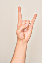 Hand of caucasian young man showing fingers over isolated white background gesturing rock and roll symbol, showing obscene horns gesture